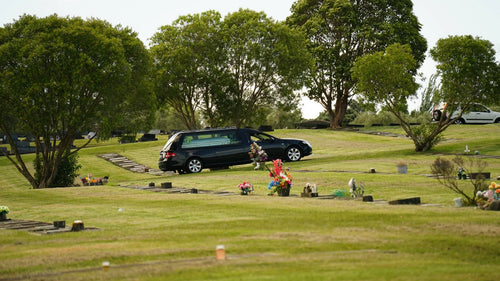 Funeral hearse at an Auckland cemetery during a Cook Islands burial service, supported by Lagoon View Funerals for Pasifika families.