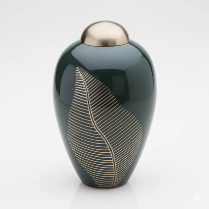 Modern metal urn for ashes in deep green with a reflective gold top and a detailed botanical leaf pattern.