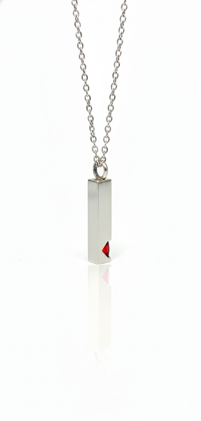 Silver bar pendant necklace with a small red gemstone inset at the bottom, hanging from a silver chain on a white background.