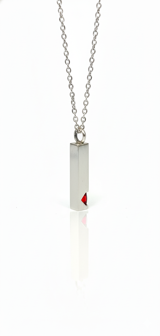 Silver bar pendant necklace with a small red gemstone inset at the bottom, hanging from a silver chain on a white background.